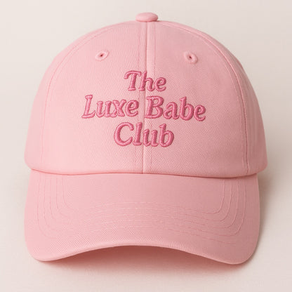 Pink cap with 'The Luxe Babe Club' text on a light pink background